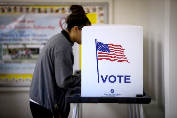 Woman with grey sweater and voting booth