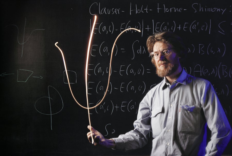 Image of a man standing in front of a chalkboard with mathematical equations