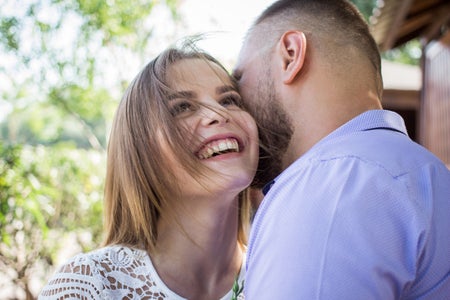 A man whispers into a woman's ear.