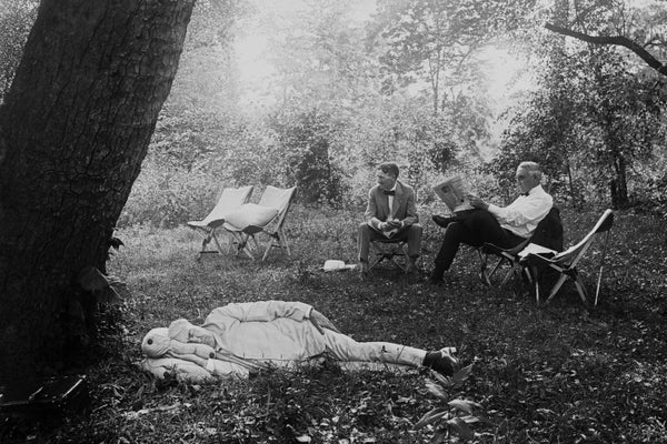 Thomas Edison sleeping under a tree in a light-colored suit.