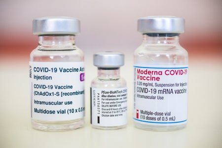 Vials of COVID vaccine with labels reading "Moderna" and "Pfizer BioNTech" clearly visible.