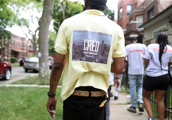 Community violence outreach worker with yellow CRED T-shirt in Chicago walking away.