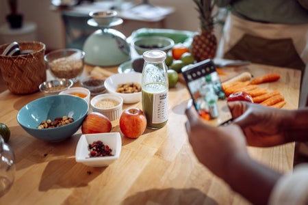 Unrecognizable man taking a photo of smoothie on a kitchen counter