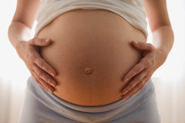 A view of a pregnant woman's hands on her stomach.