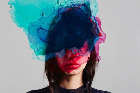 A conceptual image of a woman with multi-colored ink on her face.