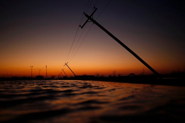 Damaged utility poles against sunset