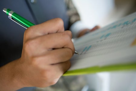 Close up of hand filling out paperwork.