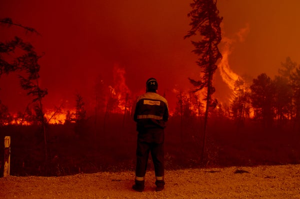 A view of a firefighter from behind as he watches the blaze.