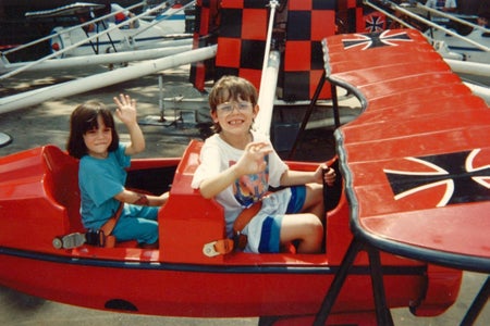 A happy boy and girl in a red baron airplan ride