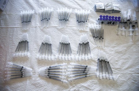 Vaccine syringes are arrayed neatly in bunches at a clinic.