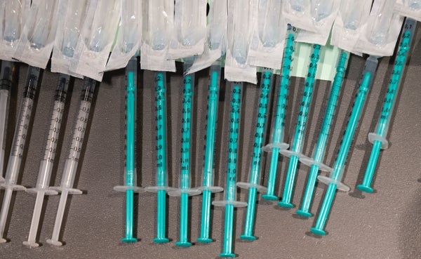A tray of white and light blue syringes filled with COVID vaccine