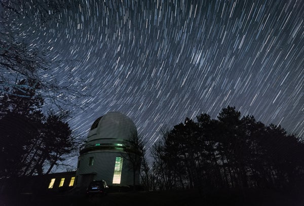 Stars trace out circles in the sky above an observatory as the Earth rotates in a long-exposure photograph.