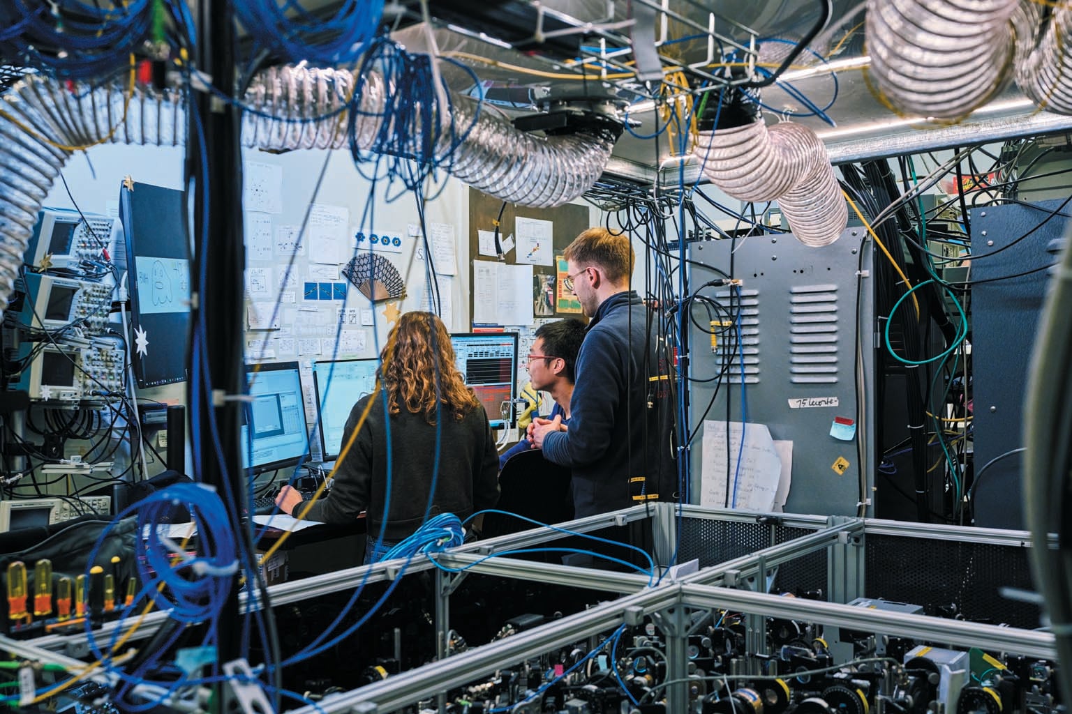 Three people gathered around a computer in a lab setting.