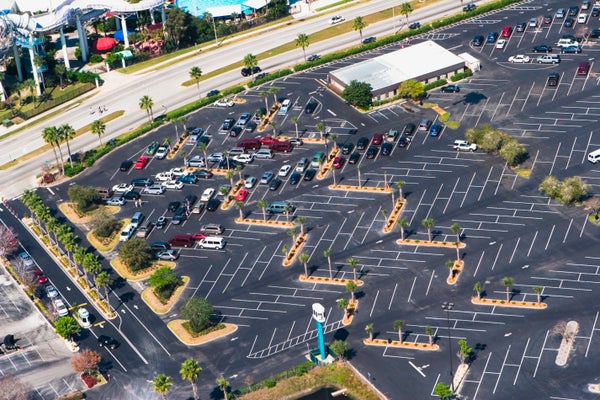 Aerial view of cars parked in a parking lot with palm trees.