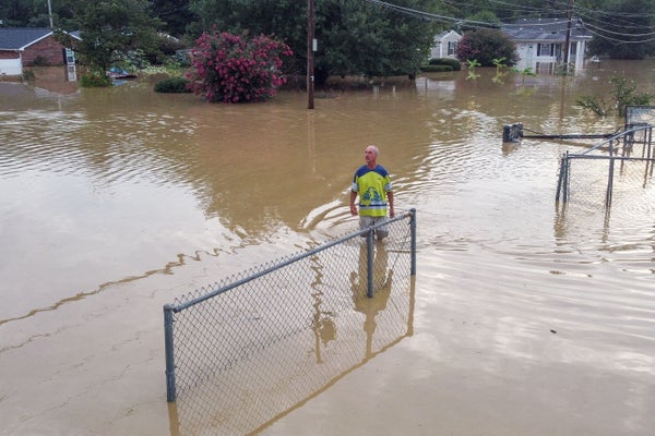 Man surrounded by muddy flood waters in neighborhood