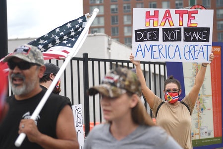 The woman is holding a sign that says "Hate does not make America great."