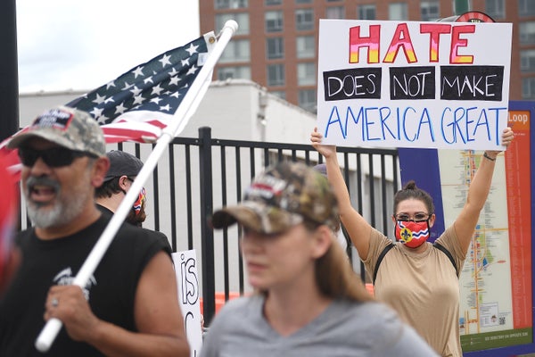 The woman is holding a sign that says "Hate does not make America great."