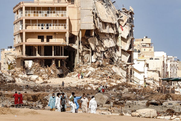 Rescue teams walk in front of collapsed buildings.