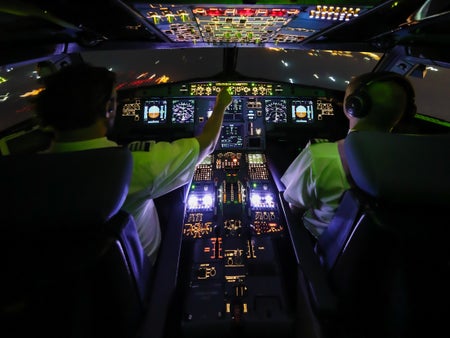 A view from behind pilots in a cockpit.