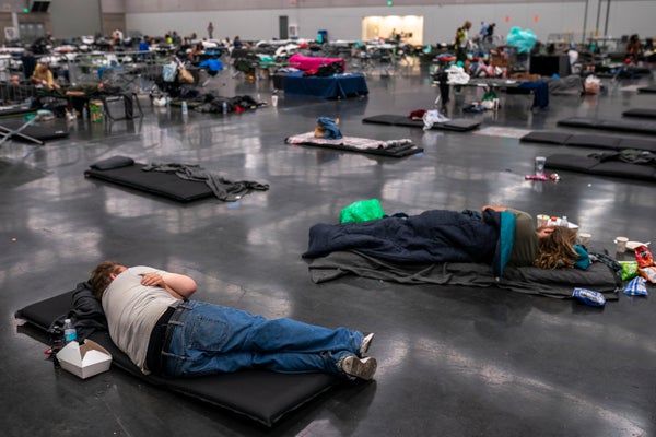 People lay on mats on the floor of a cooling center.
