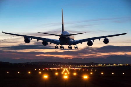 airplane just before landing in the early morning with runway lights in the foreground.