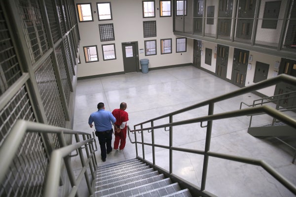 A guard escorts handcuffed detainee inside prison.