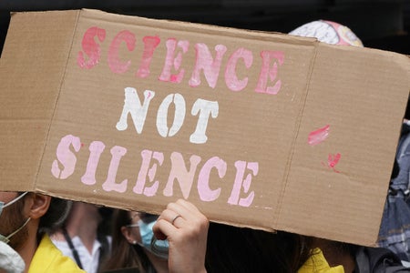 Person holding "Science Not Silence" sign