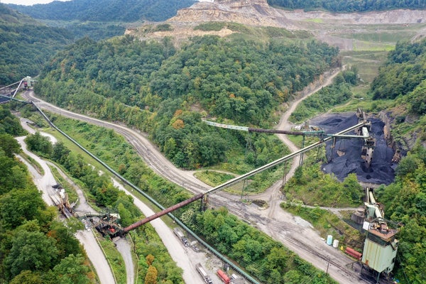 Aerial view of utility vehicles at work in mountainside coal mine.