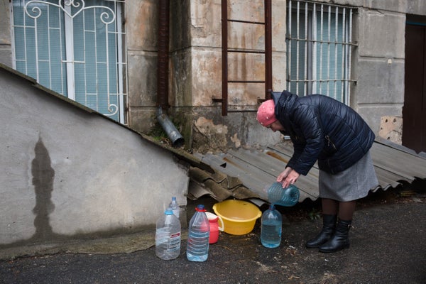 Woman collecting rain water into plastic bottles