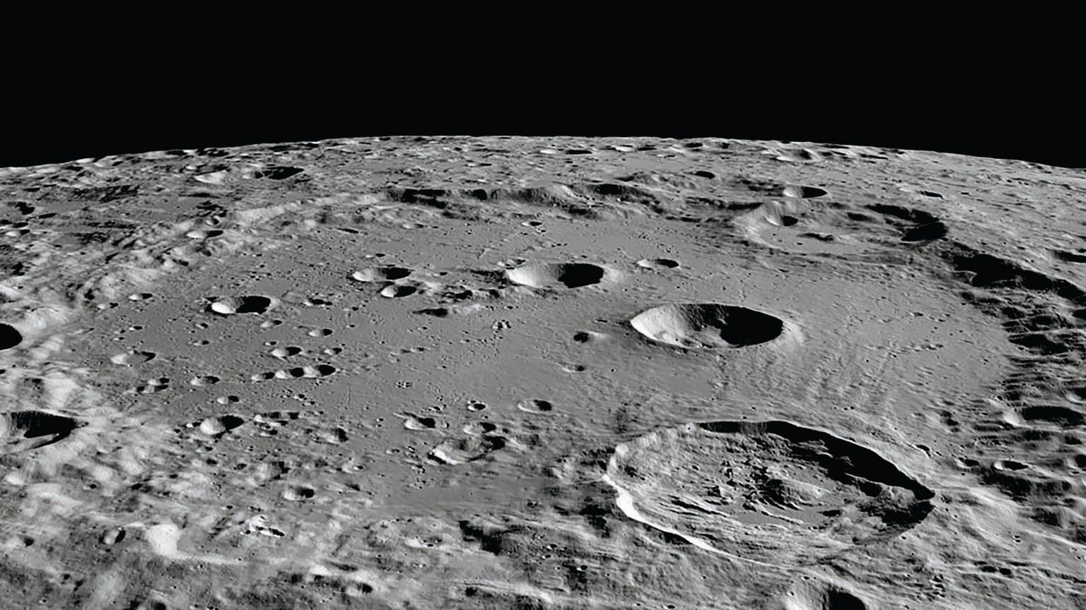 A close up view of the surface of Earth’s moon revealing craters, shown against a black background.