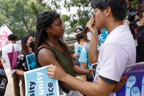 Two students react to news while holding protest signs