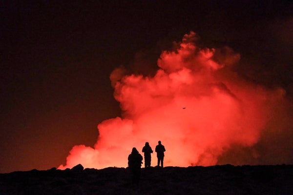 Three people silhouetted in front of billowing red smoke