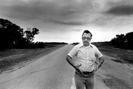 Man standing in middle of road making circle gesture with arms