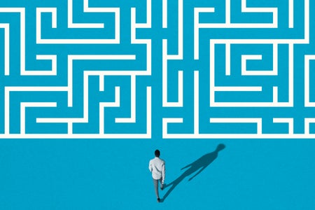 High angle rear view of young man walking towards white maze pattern over blue background.