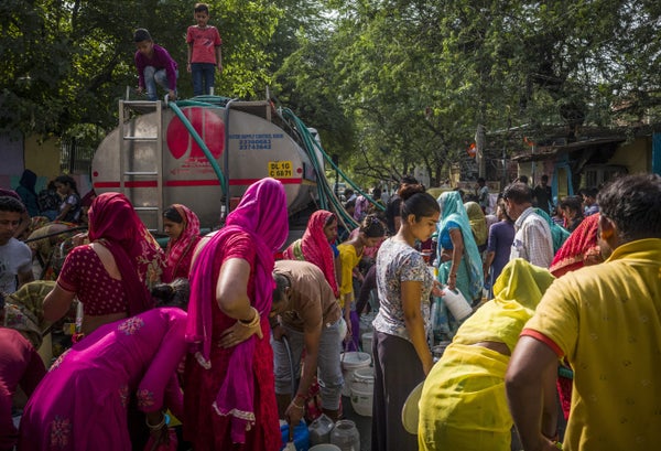 A crowd gets water from a truck in the streets of India during heatwave