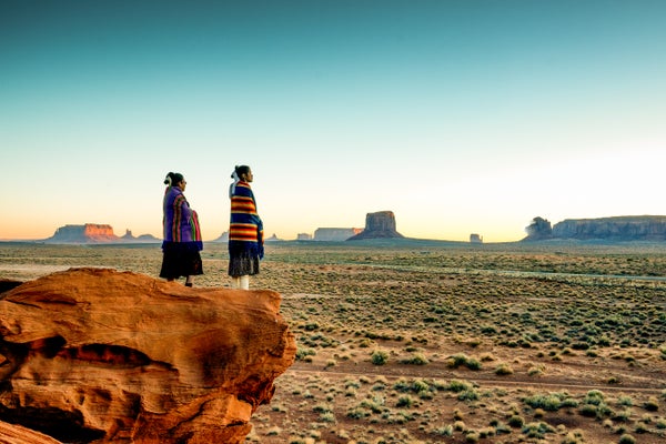 Navajo sisters look out over Monument Valley.