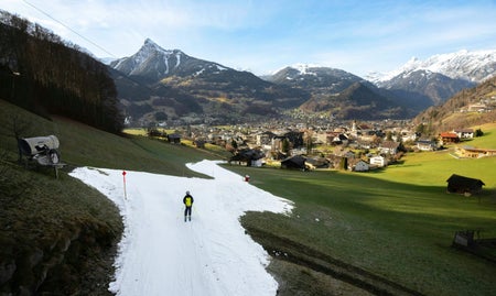 skier on a slope through green landscape with mountains