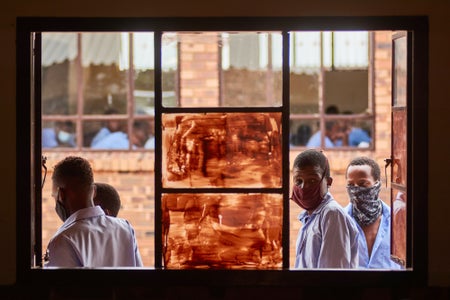 Masked students peer into a window