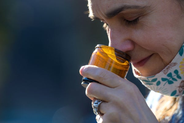 Woman smelling from a brown jar.